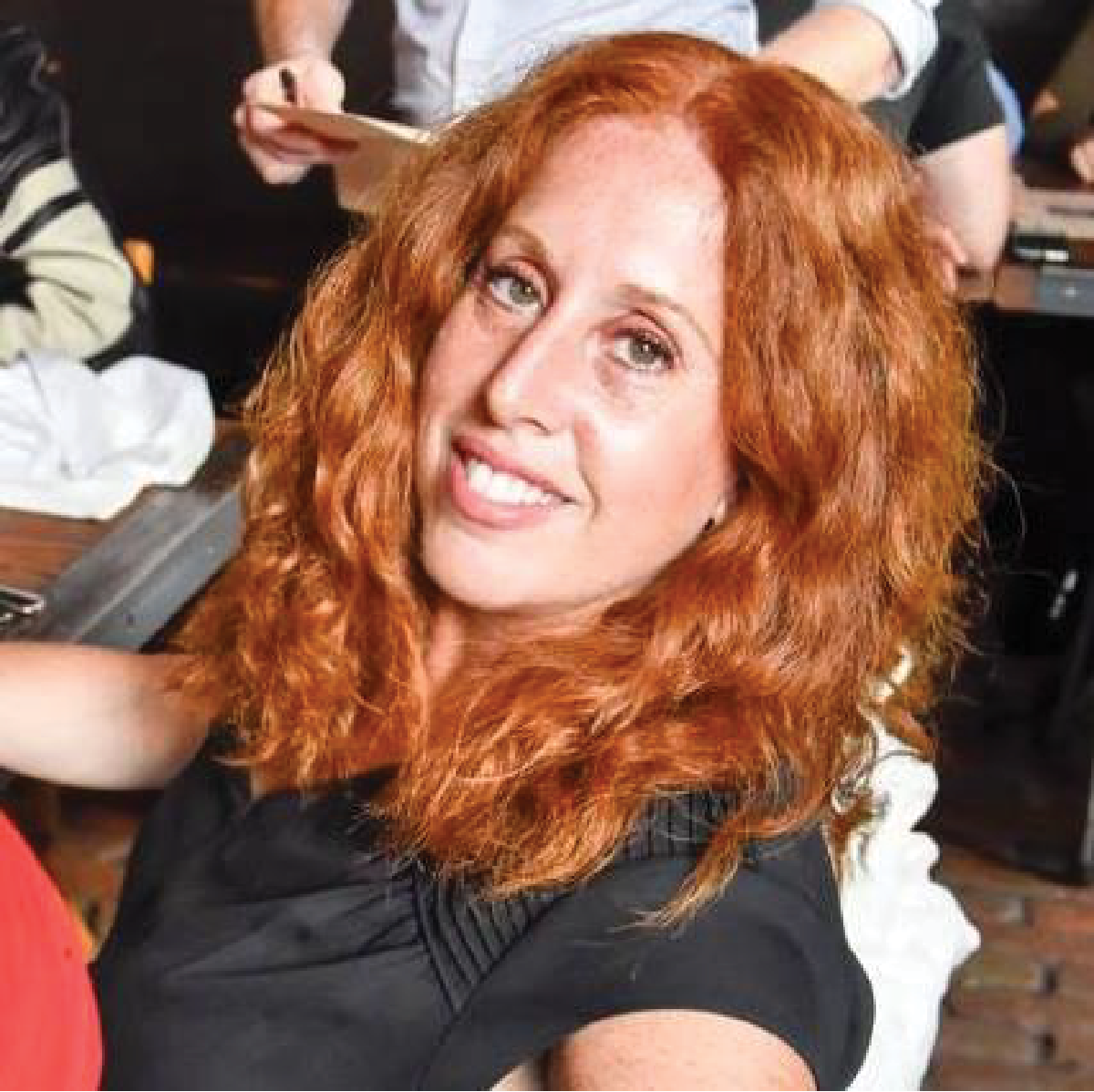 A woman with red hair sitting in front of other people.
